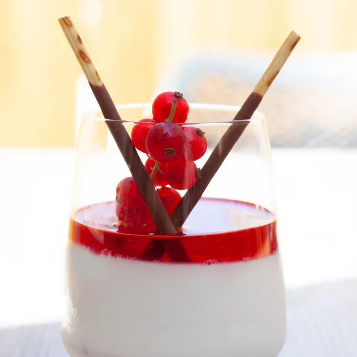 Dessert en verrine nappé de coulis rouge, groseilles et bâtonnets de chocolat